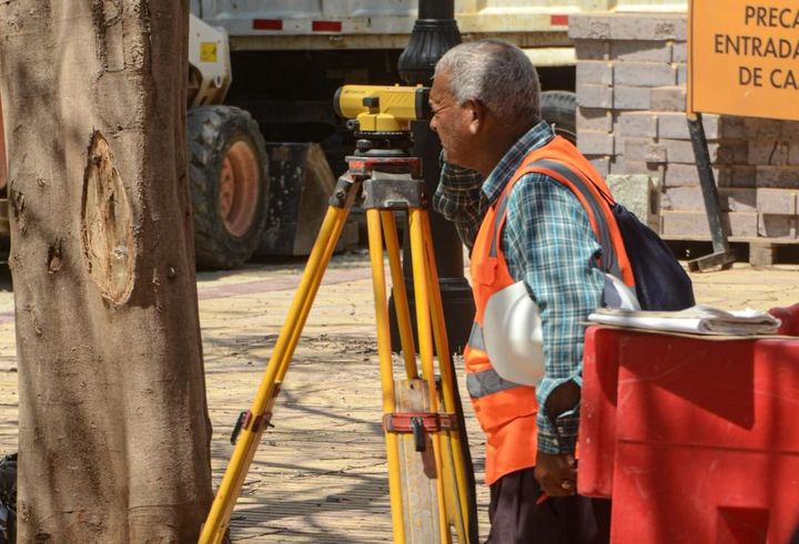 Skilled trades team reviews project details on a rugged tablet, demonstrating efficient digital workforce management on a busy construction site.