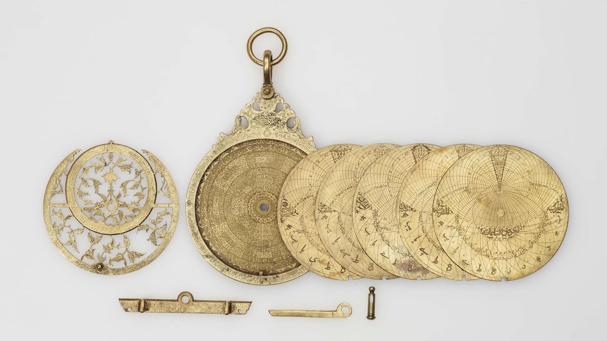 A brass planispheric astrolabe with its interchangeable plates laid out beside it, Khalili Collection of Islamic Art