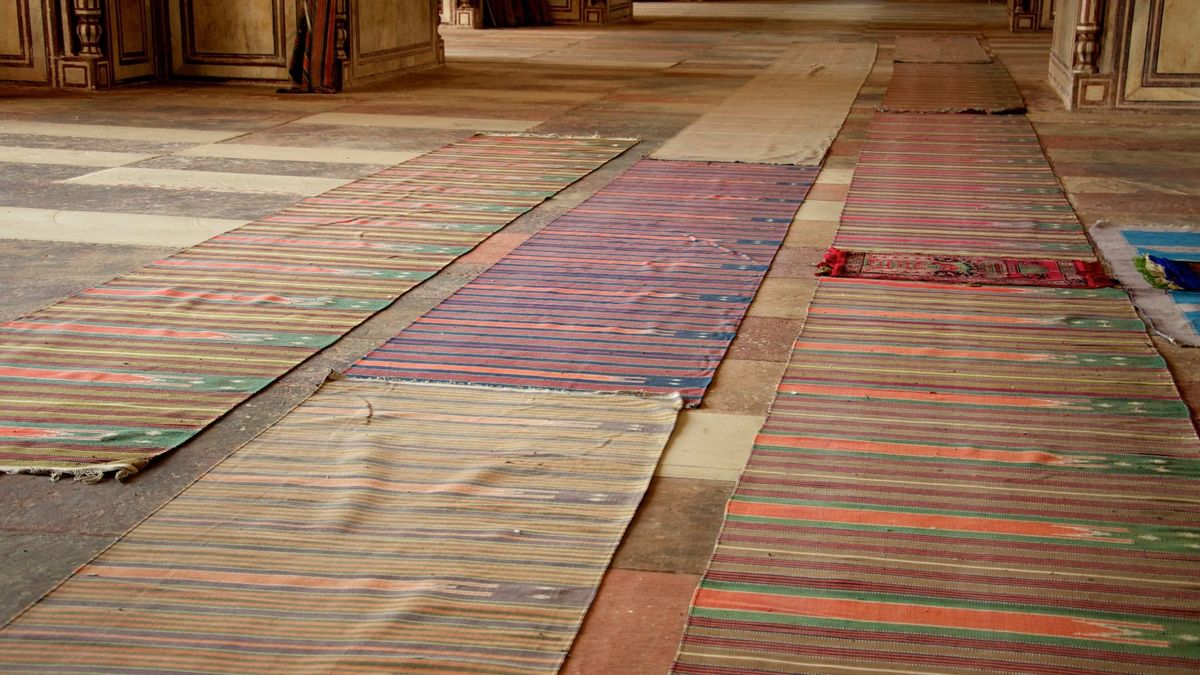 Rows of striped prayer mats laid out on the floor of an empty prayer hall at the Jama Masjid