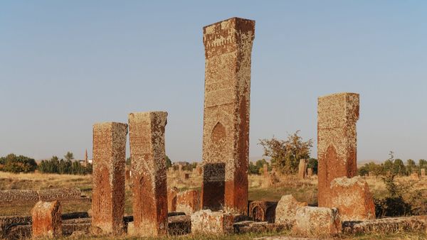 Tall carved Seljuk headstones standing in the open grassland of the old Muslim cemetery at Ahlat, eastern Turkey