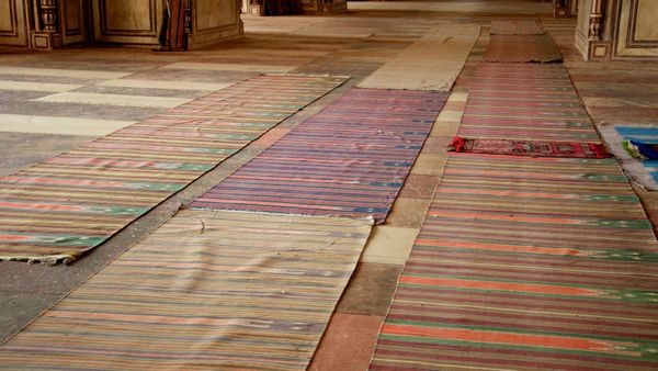 Rows of striped prayer mats laid out on the floor of an empty prayer hall at the Jama Masjid