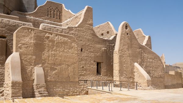 Restored mud-brick walls and buttressed towers of the At-Turaif district in Diriyah, Najd, Saudi Arabia, under a clear blue sky