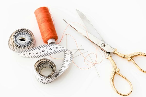 Scissors, measuring tape and orange thread.