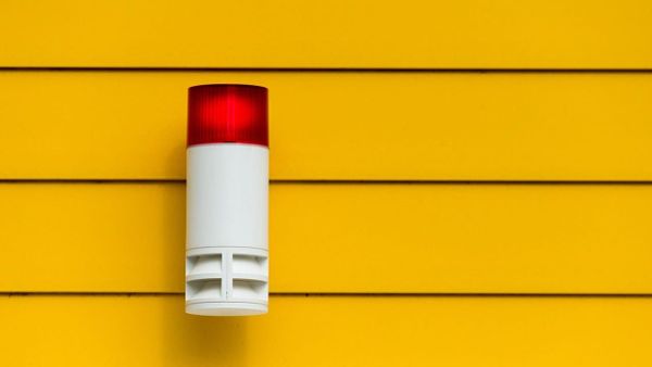Exterior alarm siren with red strobe mounted on siding