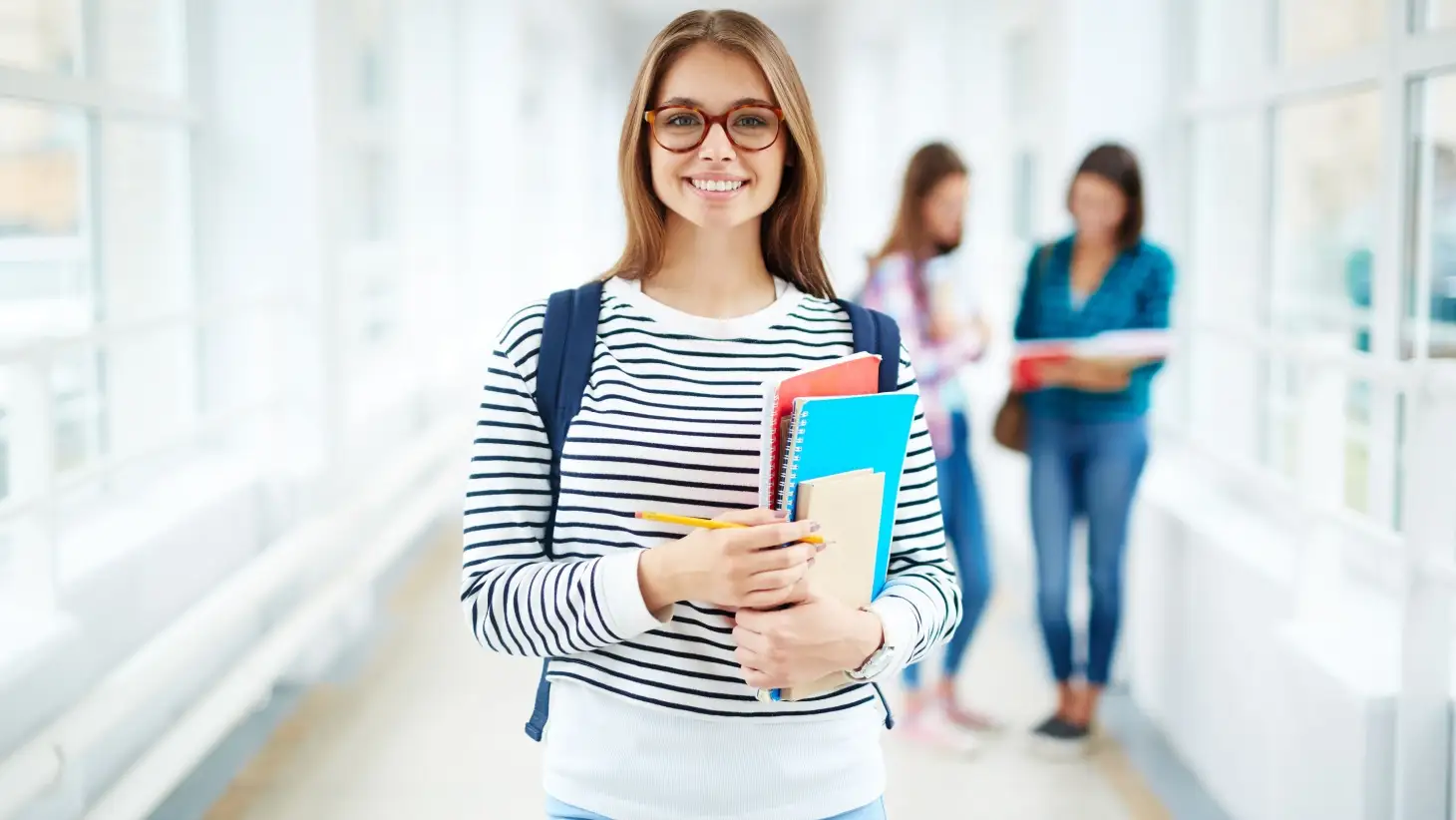student holding books - Easiest College Majors   