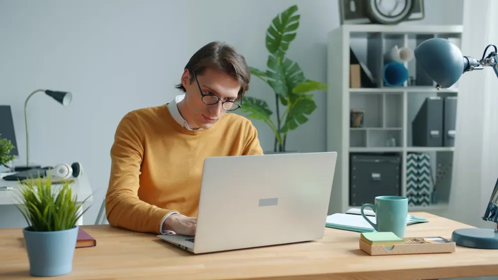 student using a grey laptop - Common App Essay Prompts