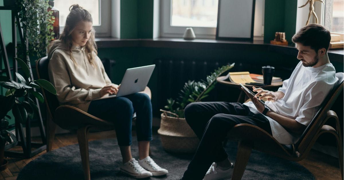Couple sitting apart at home working on laptops