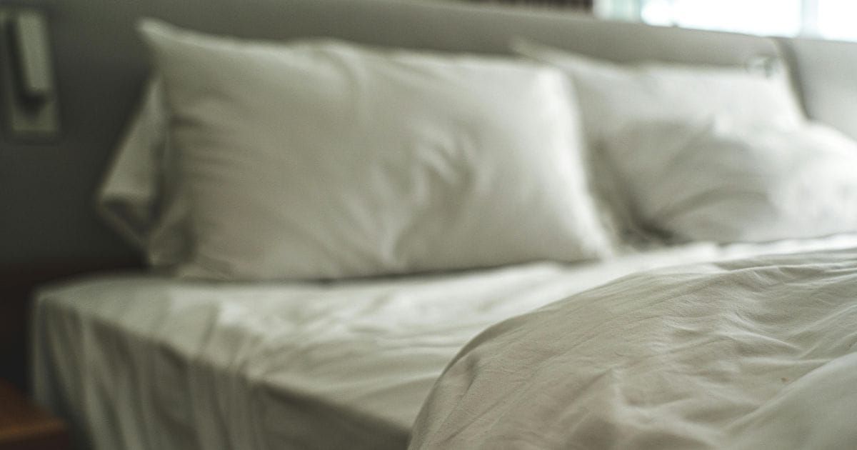 Soft focus unmade bed with white rumpled sheets and pillows in a quiet bedroom