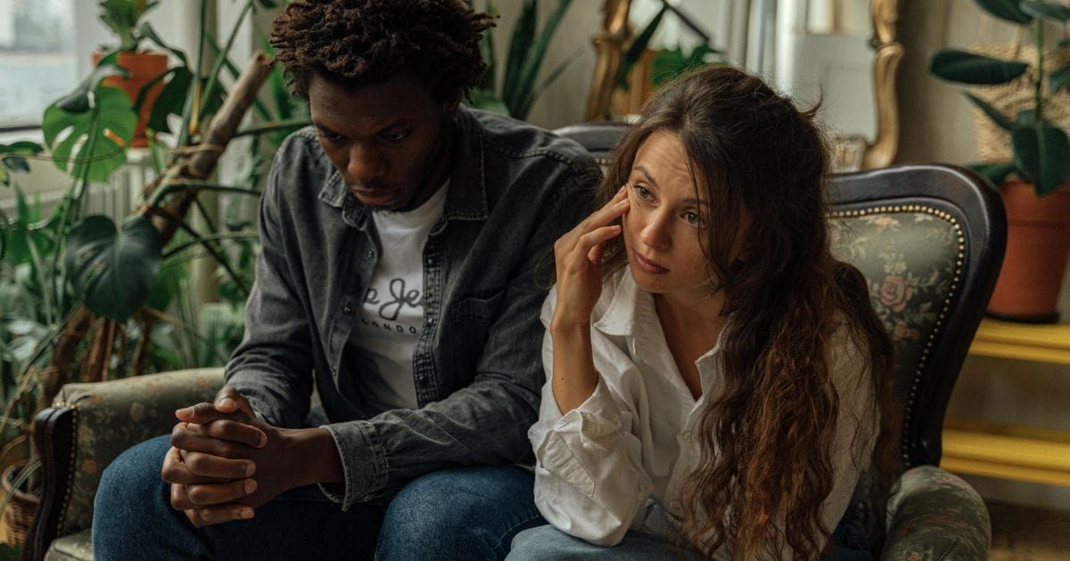Couple sitting together in chairs each looking away quietly
