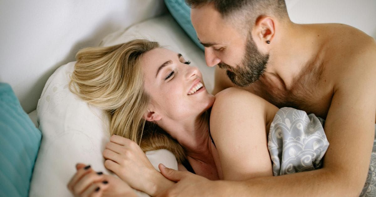 Couple laughing together in bed in an intimate and playful moment