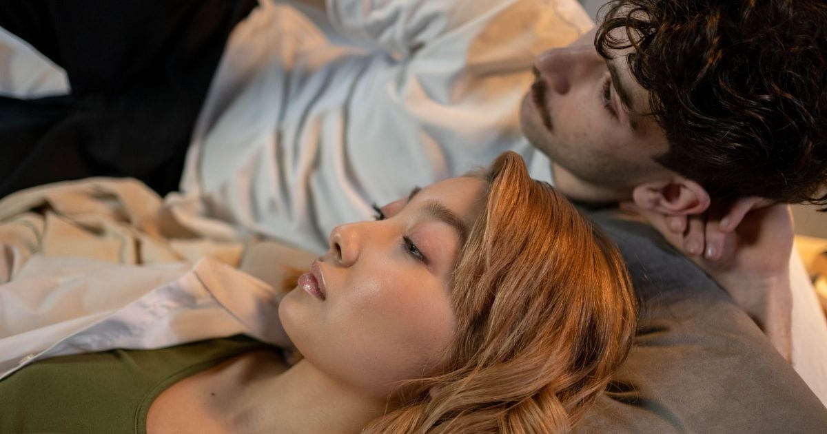 Couple lying in bed, both looking away in quiet thought
