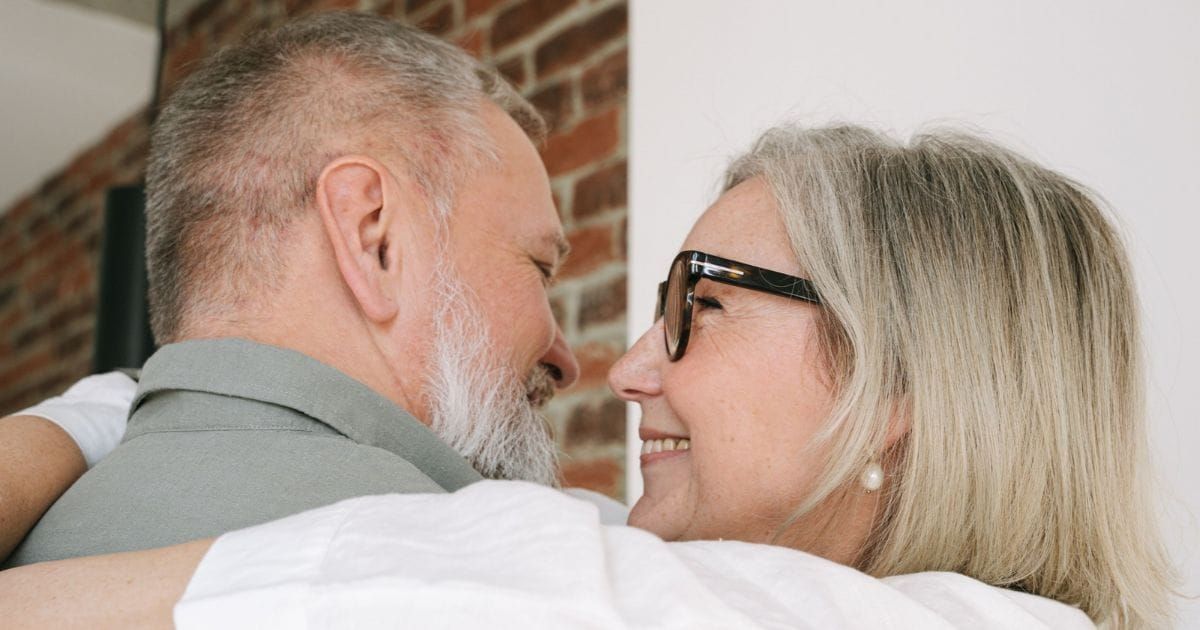 Mature couple embracing, smiling at each other.