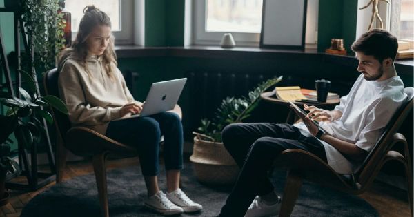 Couple sitting apart at home working on laptops