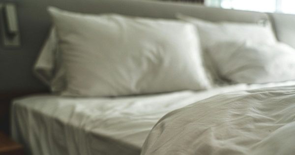 Soft focus unmade bed with white rumpled sheets and pillows in a quiet bedroom