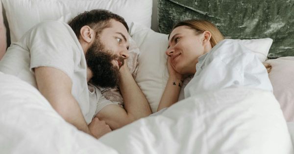 Couple lying in bed facing each other smiling in the morning