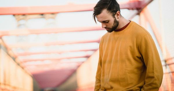 Young man standing alone on bridge looking down in quiet reflection