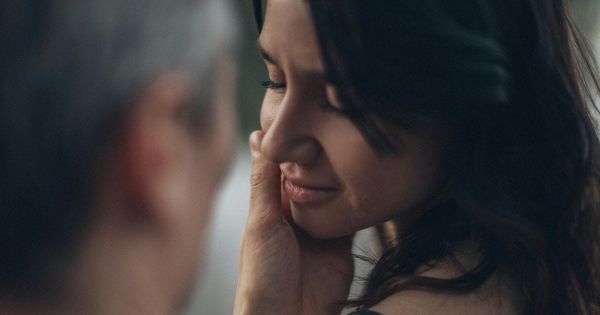 Man tenderly cupping woman's face as she closes her eyes in a moment of trust and vulnerability