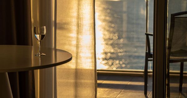 Hotel room window at golden hour with wine glass on table
