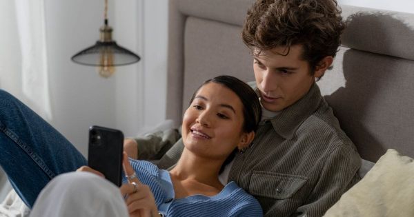 Couple looking at a phone together, smiling, in bed