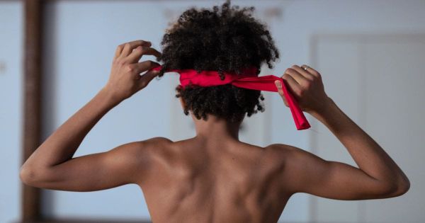 Woman tying on a blindfold, viewed from behind
