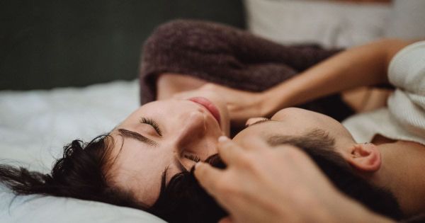 Couple lying close together in bed, foreheads nearly touching