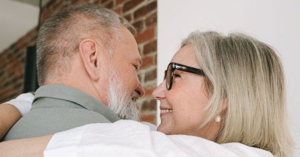 Mature couple embracing, smiling at each other.