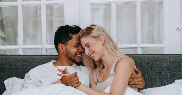 Couple laughing together, foreheads touching, holding hands.