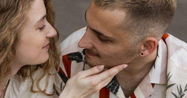 Couple close together, her hand on his face, both looking at each other.