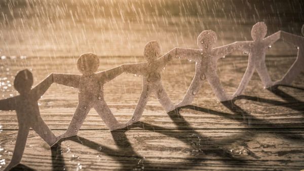Rain soaks a paper chain of people