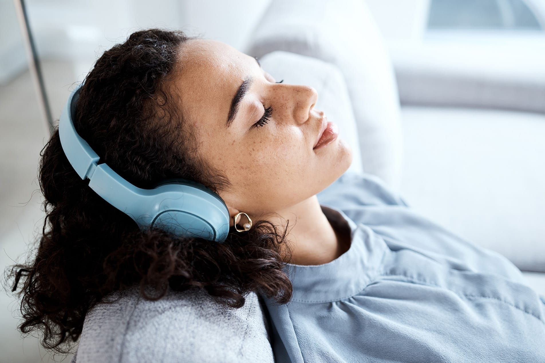 Young woman relaxing with headphones on and eyes closed listening to meditative music for ketamine treatment sessions 