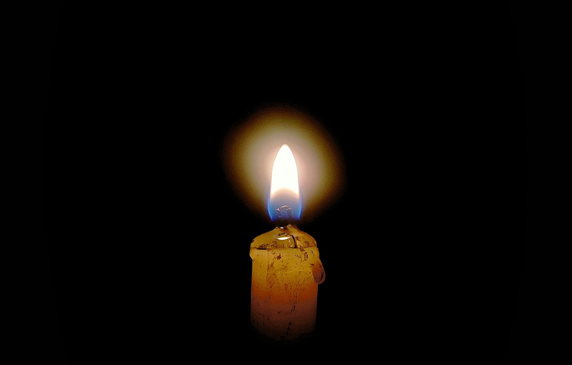 a lit candle in the middle of a dark room