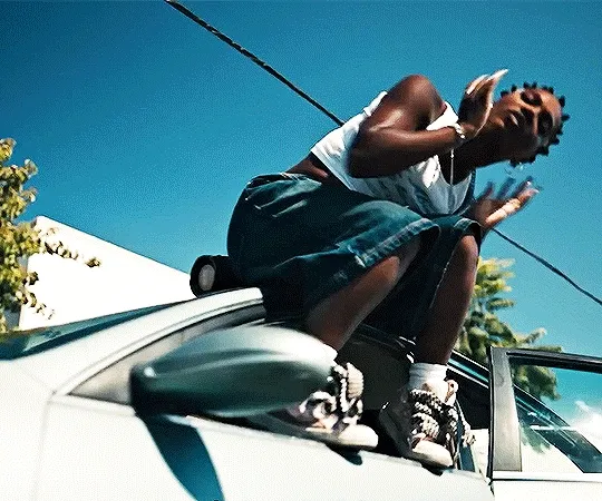 gif of Doechii in the video for 'nissan altima' where she's rapping on top of a moving car that's being towed.