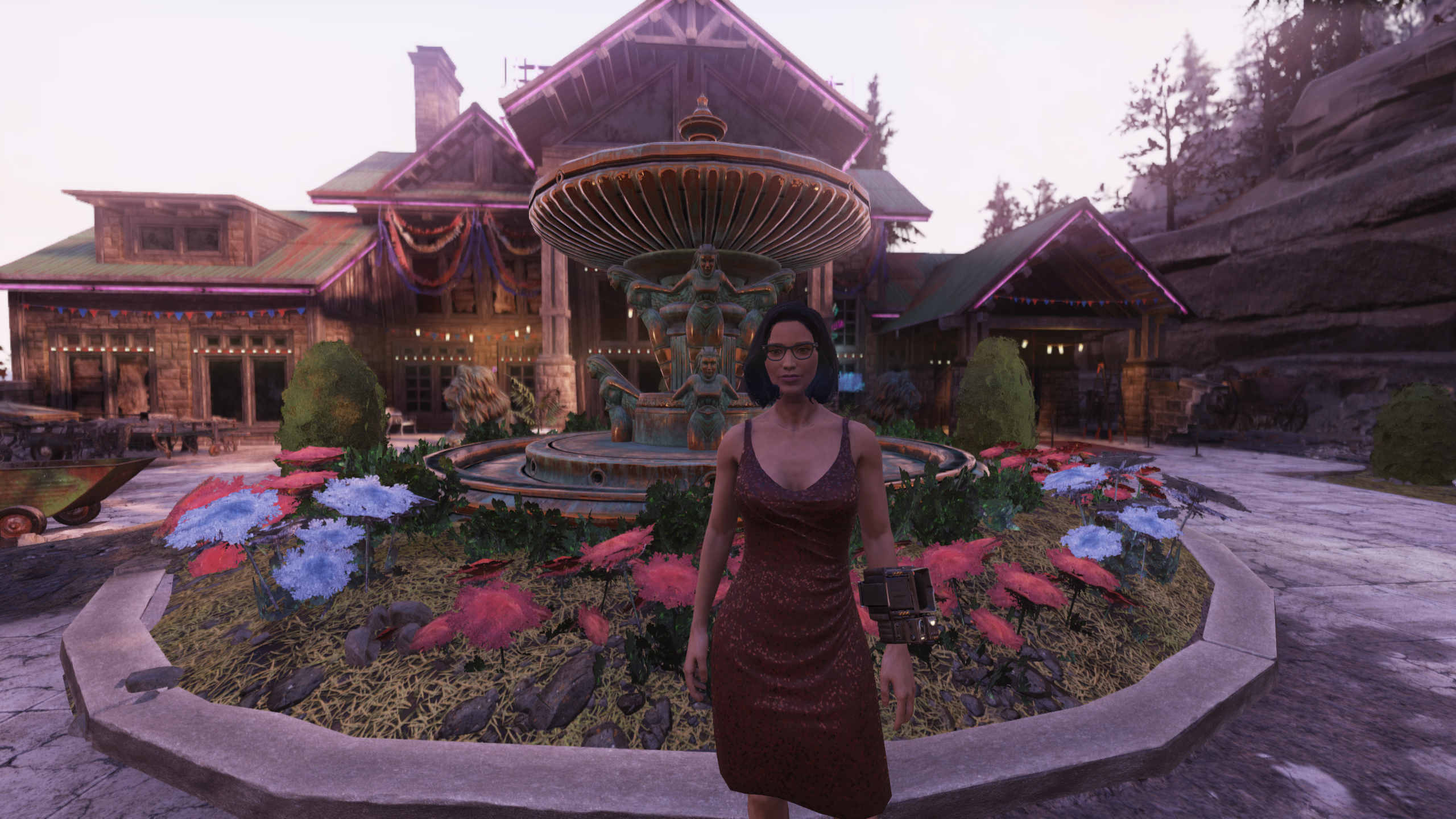 Female player character with dark hair wearing glasses and a strappy red dress in front of a fountain filled with flowers outside a large house. 
