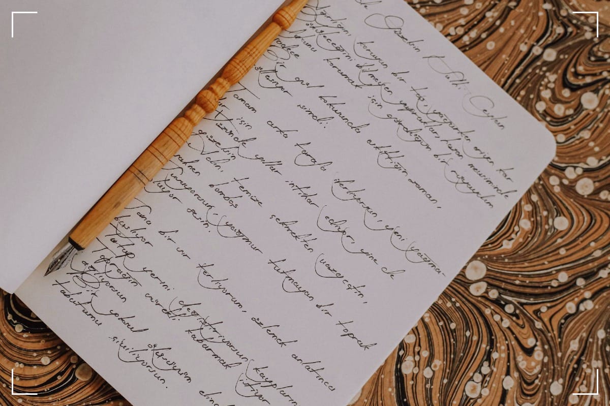 Elegant wooden fountain pen laying on a notebook filled with cursive handwriting.