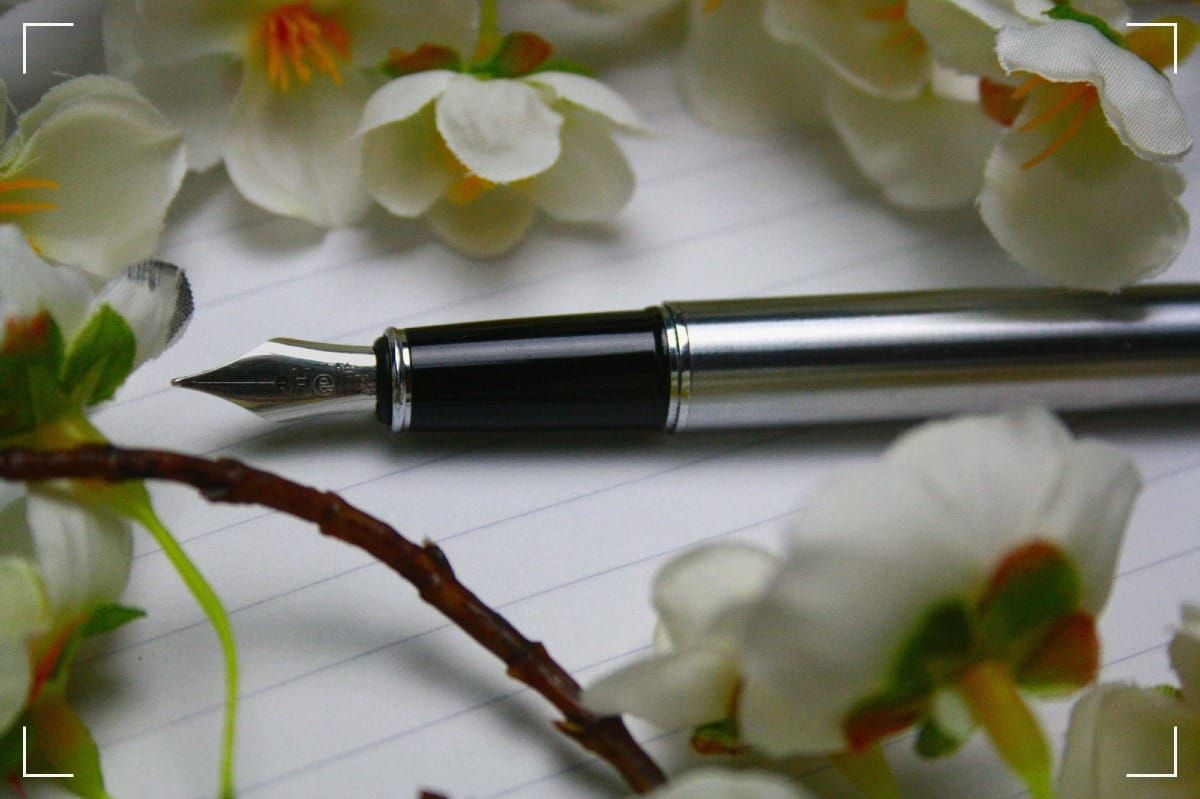 A fountain-pen surrounded by flowers.