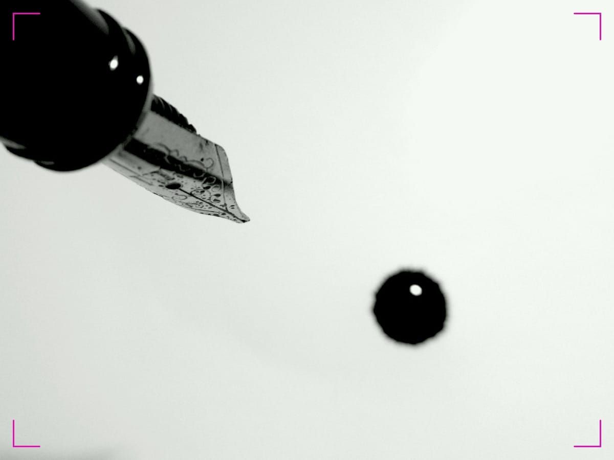 A fountain pen leaking a drop of ink on a paper