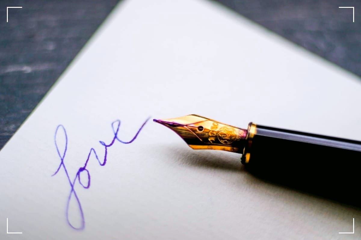 Nib and section of a fountain-pen lying on a notebook with "love" writtten on the page.