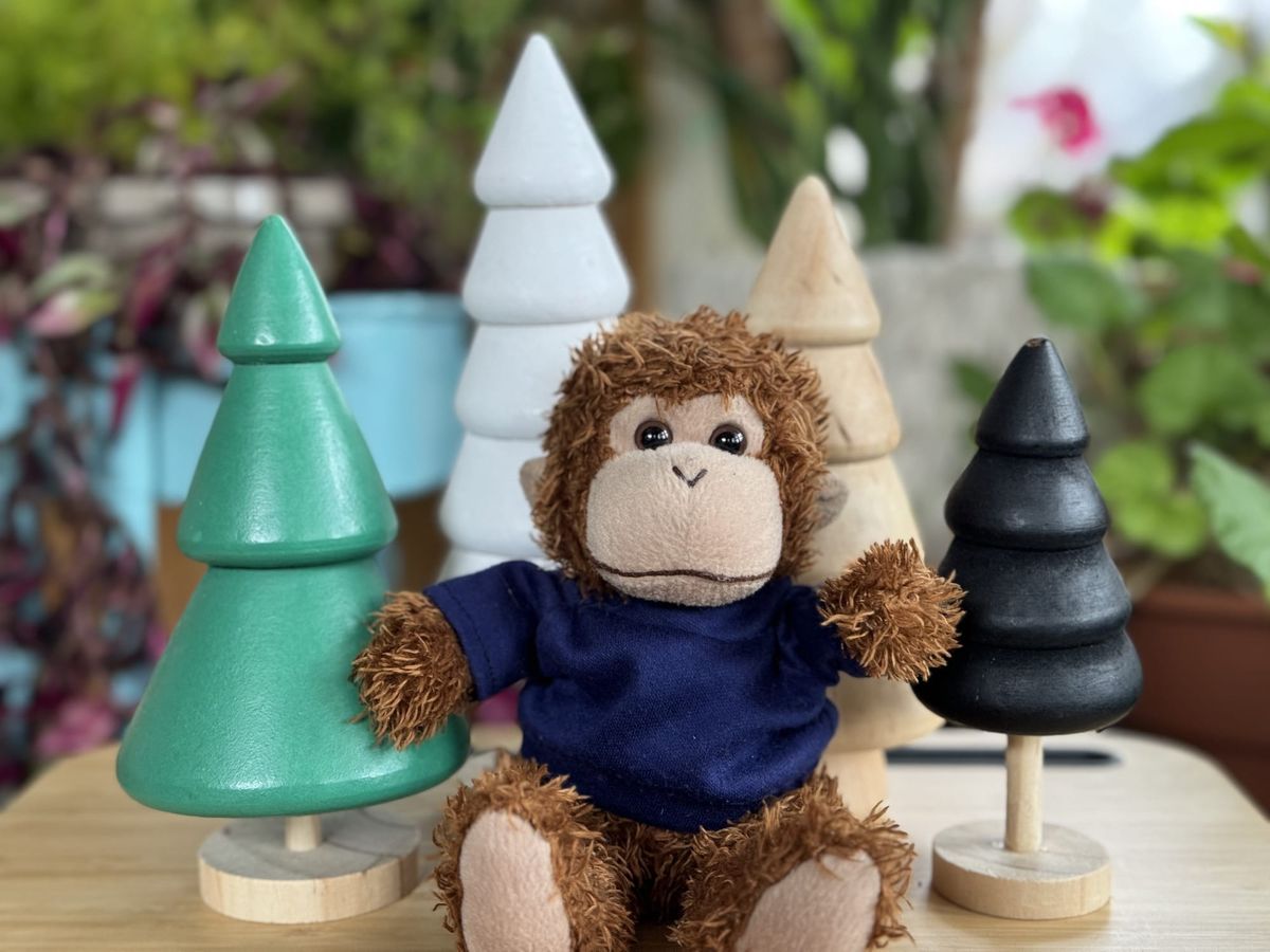 Bob T. Monkey sitting in front of some tree-shaped holiday decorations.
