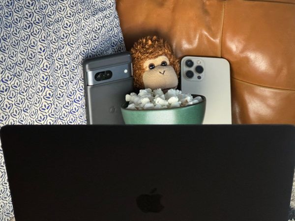 Bob T. Monkey demonstrates multitasking with two phones, a laptop, and a bowl of popcorn.