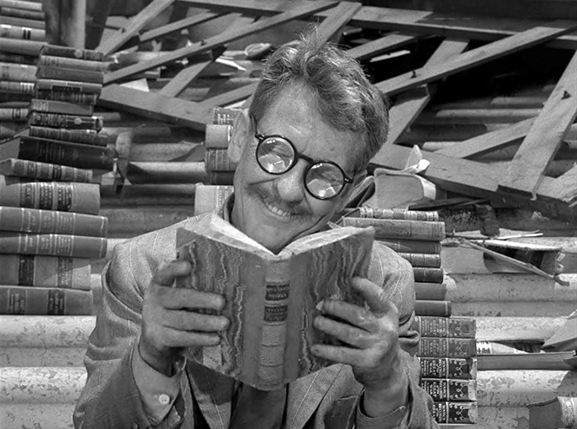 A man with thick glasses, surrounded by books he’ll never get to read, smiling like he has all the time in the world. From the classic “Twilight Zone” episode “Time Enough at Last.”