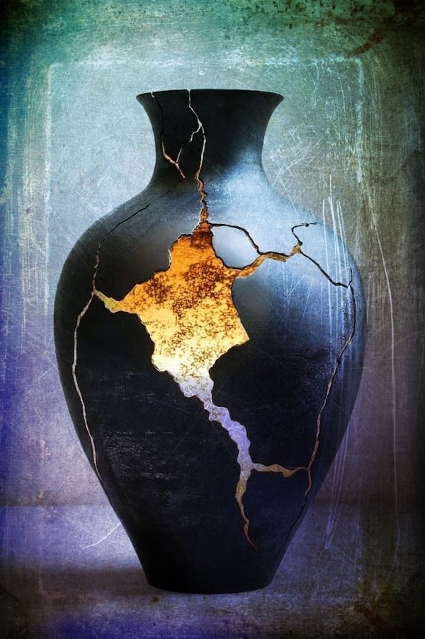  dark ceramic vessel cracked open, warm golden light pouring through the breaks, against a weathered blue-green background.