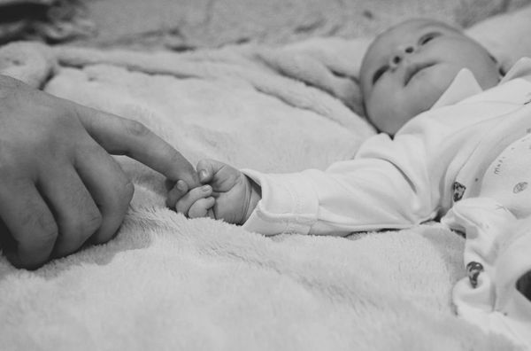 A human baby grasps an adult finger.
