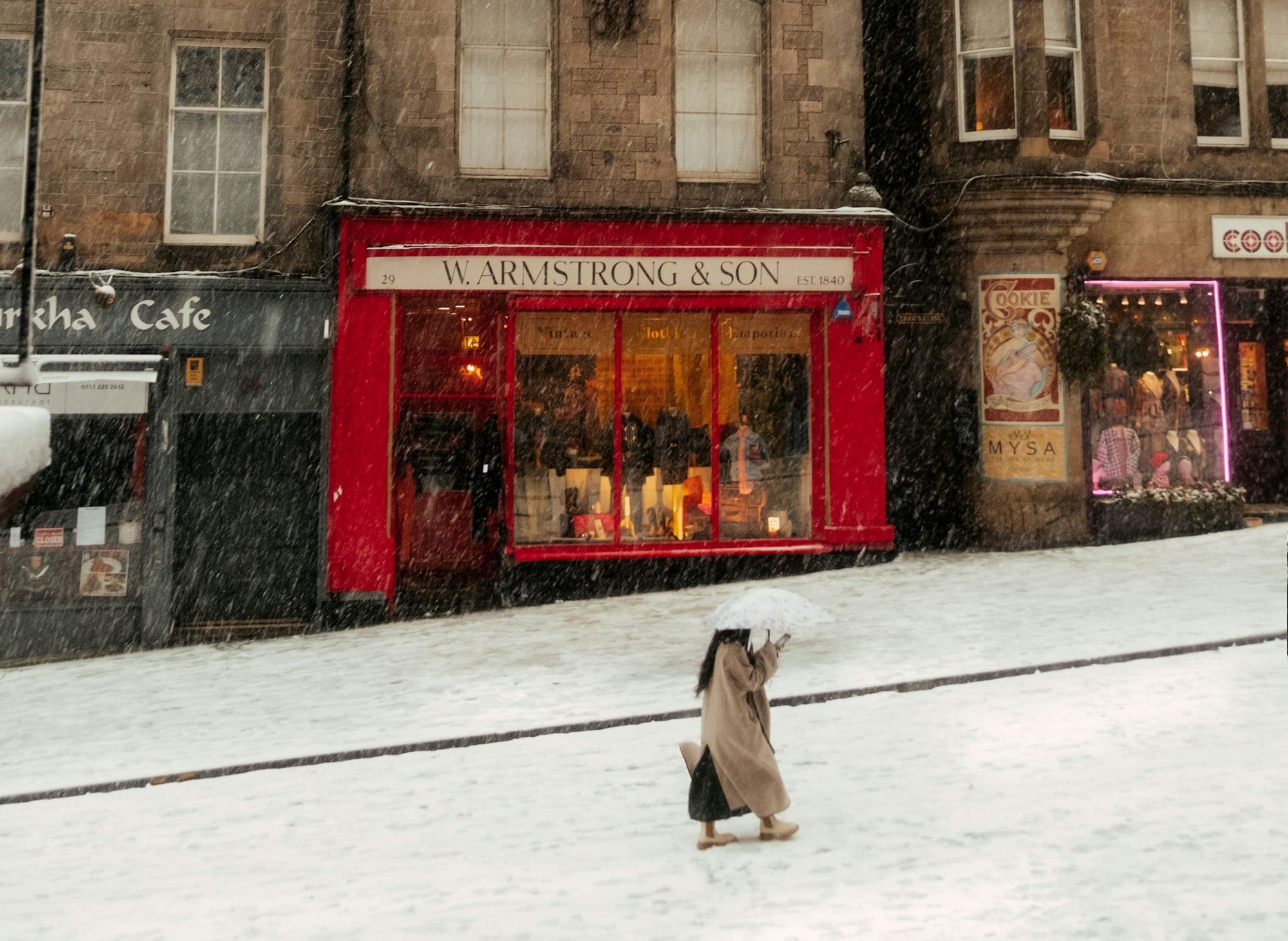 A dog is sitting in the snow in front of a building