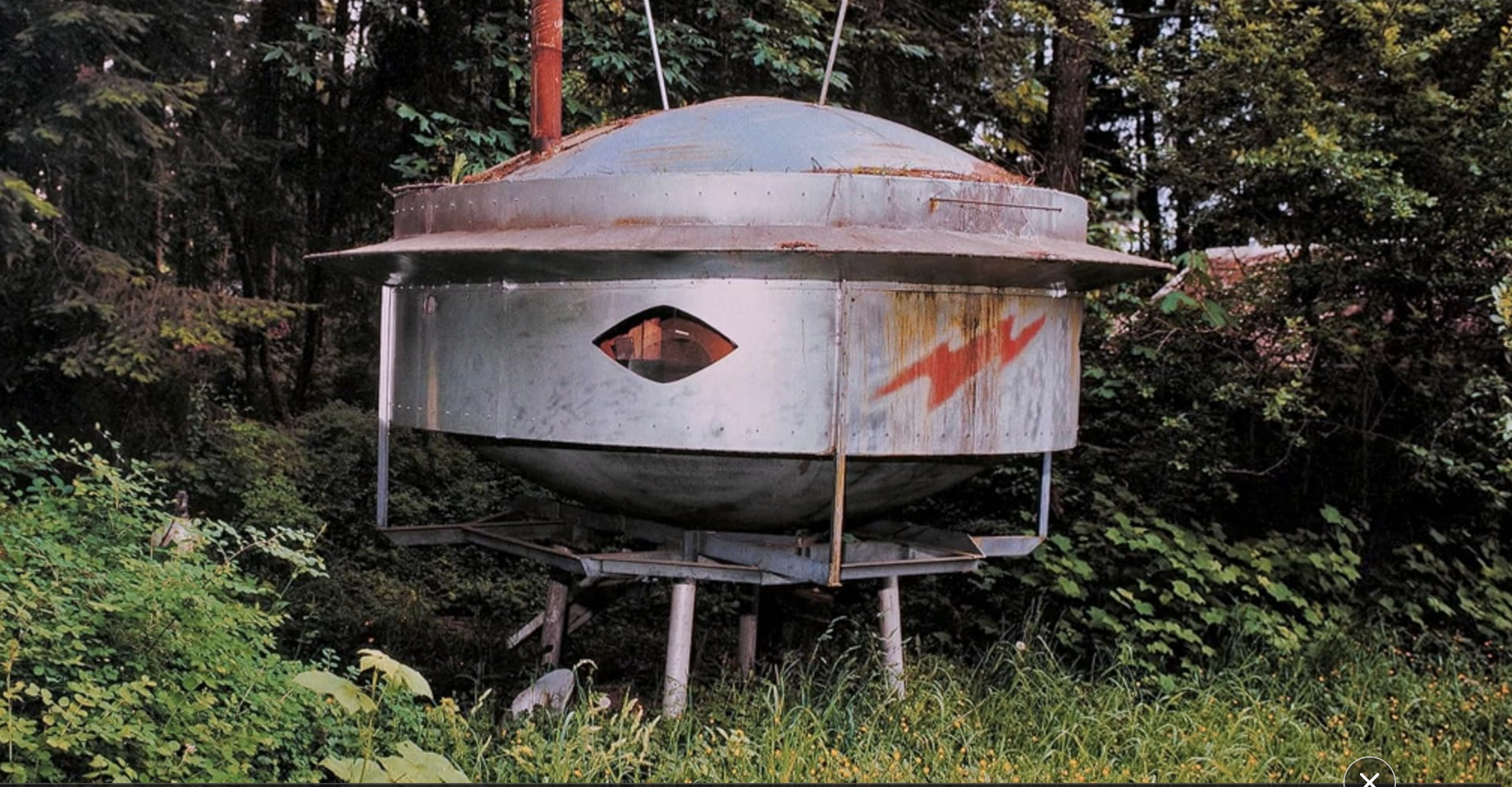 a steel and slightly rusty replica of a classic UFO with a red lighting bolt on the side