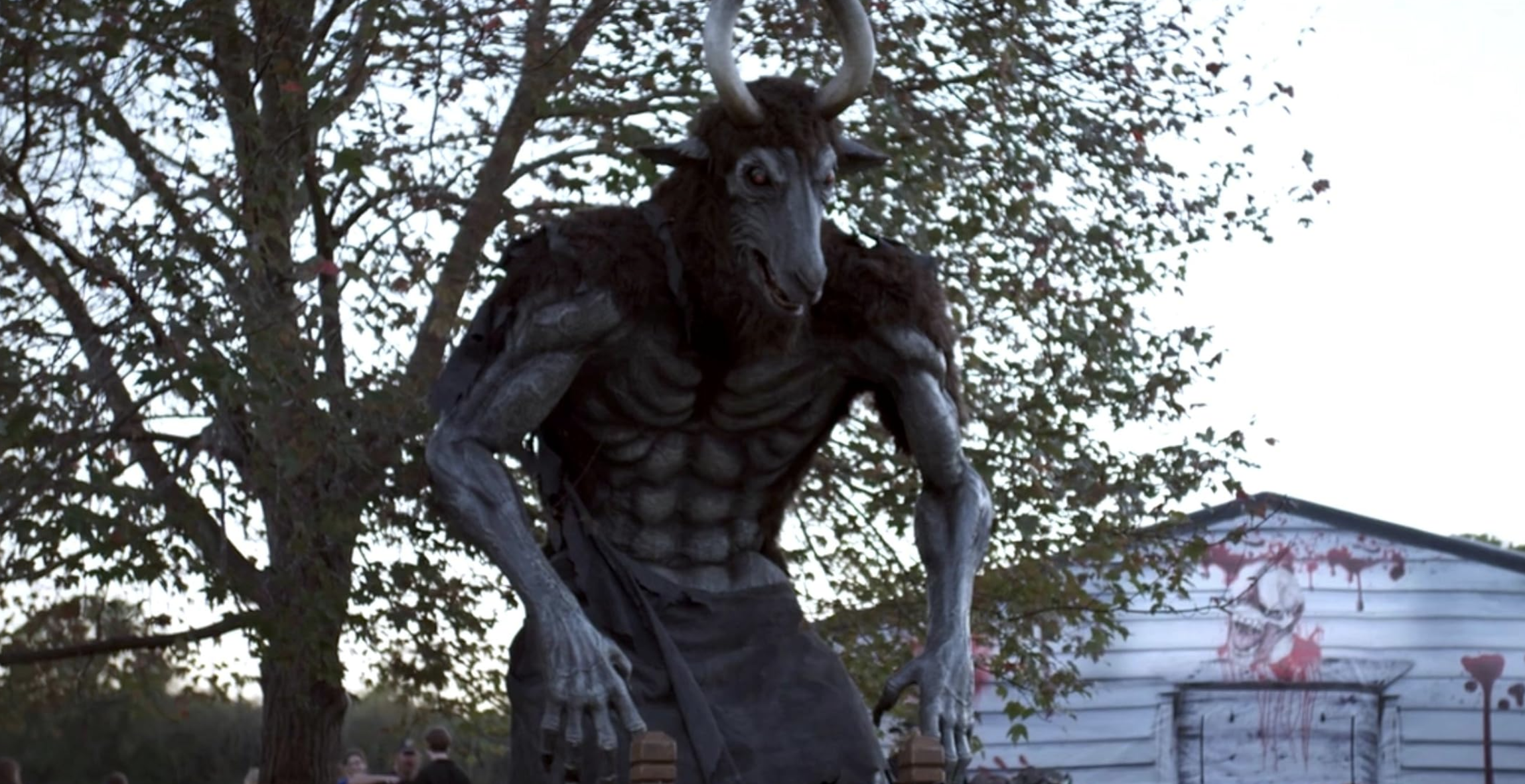 statue of a goatman monster with a blood splattered shed in the background