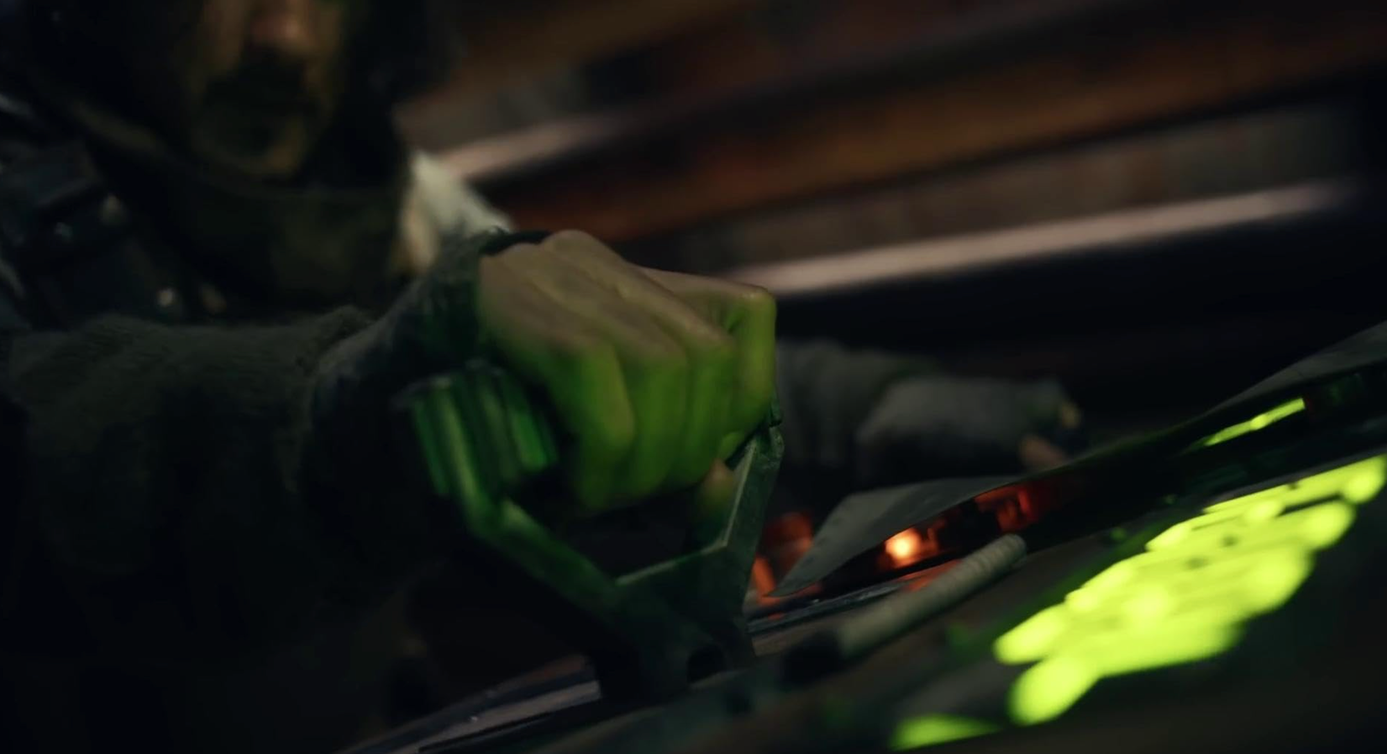 A man reaches across an illuminated console to pull a lever.