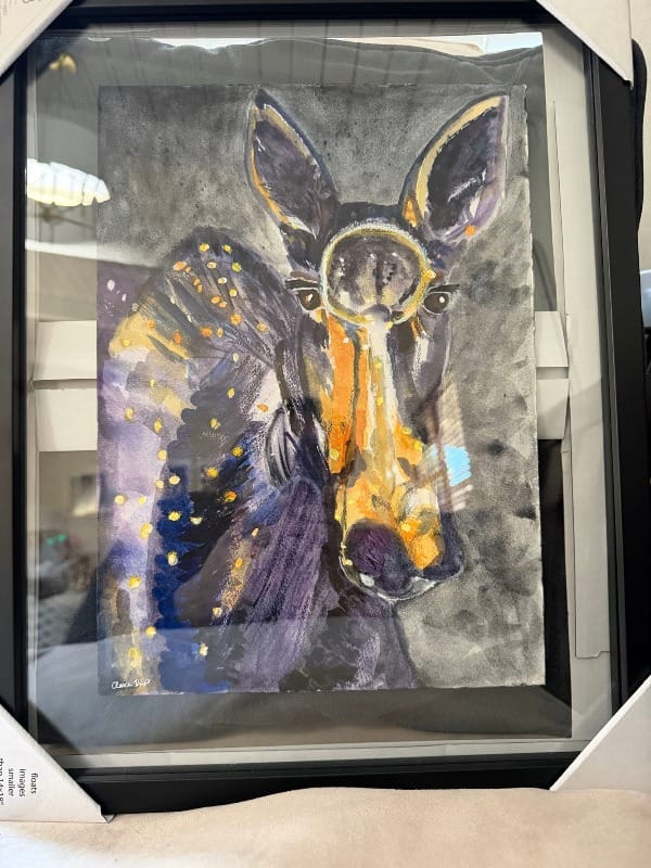 Shows a painting of a female moose in a glass frame, prior to being shipped