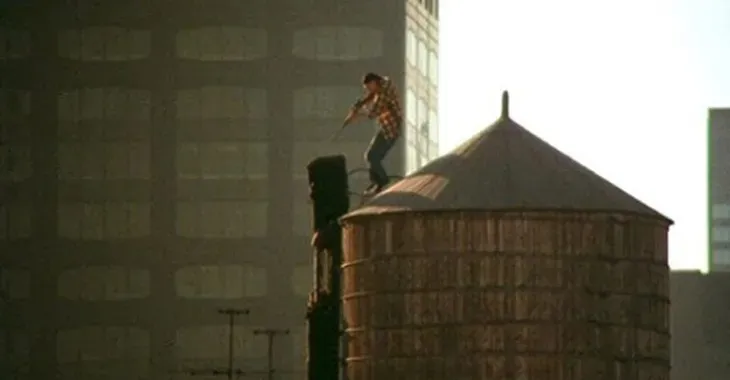 A sniper takes aim from a rooftop water tower in a still from GOD TOLD ME TO.