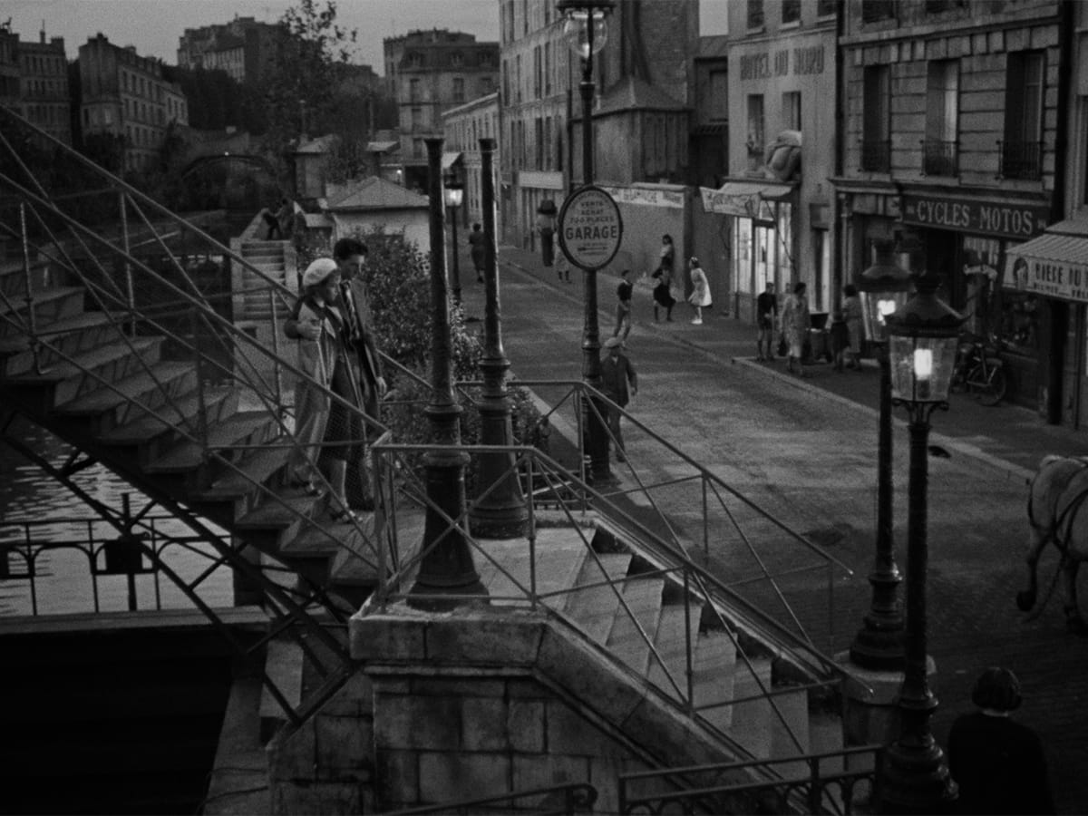 A couple descends a staircase into the Paris streets in a still from HOTEL DU NORD.