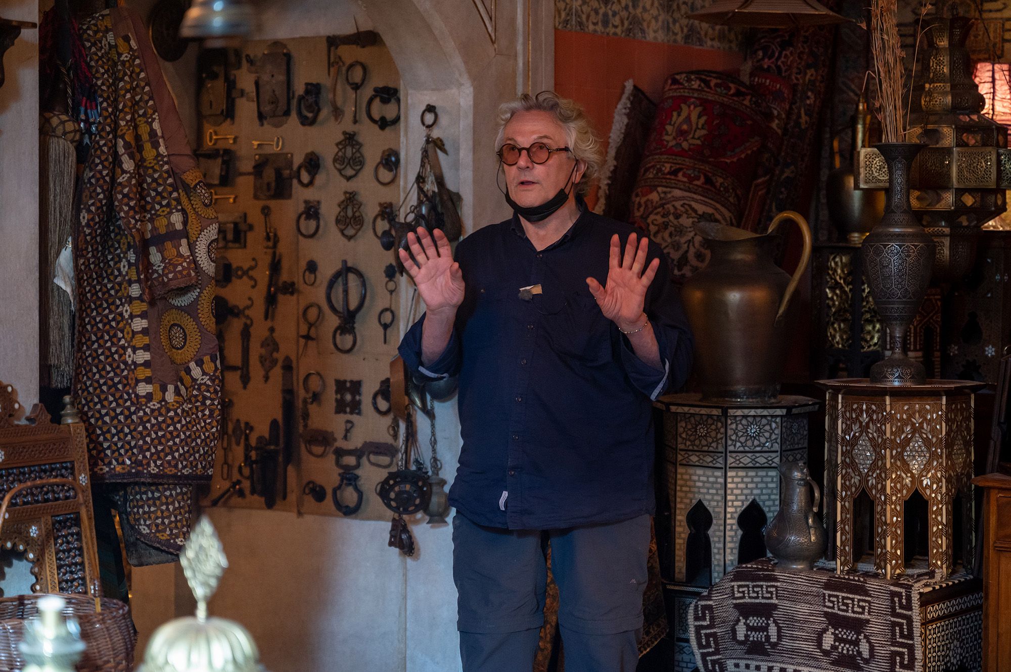 George Miller gestures on the set of an antique shop in a production photo from THREE THOUSAND YEARS OF LONGING.